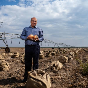 Businessman Posing with Onions in field with irrigation equipment