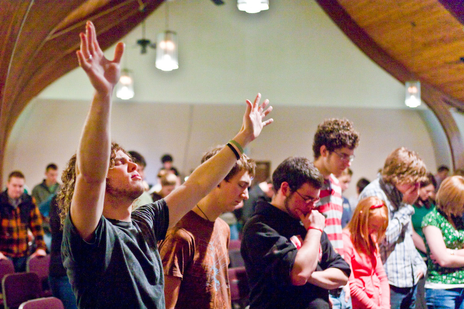 Man raises hand while others pray at the Red Sea Church in St. Johns Oregon