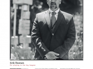 Erick Thorsen stands outdoors in suit in environmental portrait