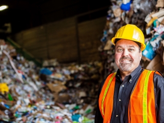 CEO of Farwest Fibers standing before mountain of recycling