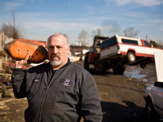 Heber Thurston, owner of AAA Auto Wrecking holds a catalytic converter in Portland junkyard