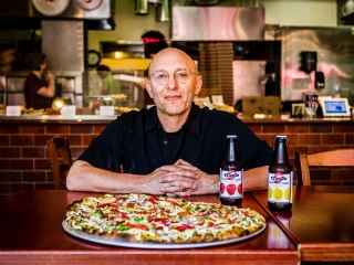 David Yudkin, Founder of Hot Lips Pizza pictured behind pizza pie