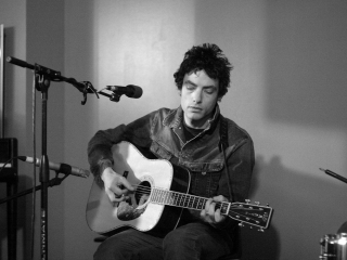 Jakob Dylan strumming guitar during a live performance for Kink 101.9 fm