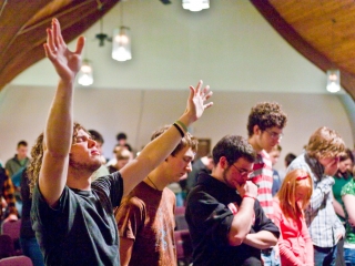 Man raises hand while others pray at the Red Sea Church in St. Johns Oregon