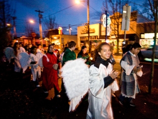 Procession of children wearing angel wings walk down street during St. Johns Posada