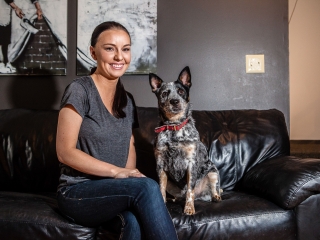 Woman sitting with her dog on black couch